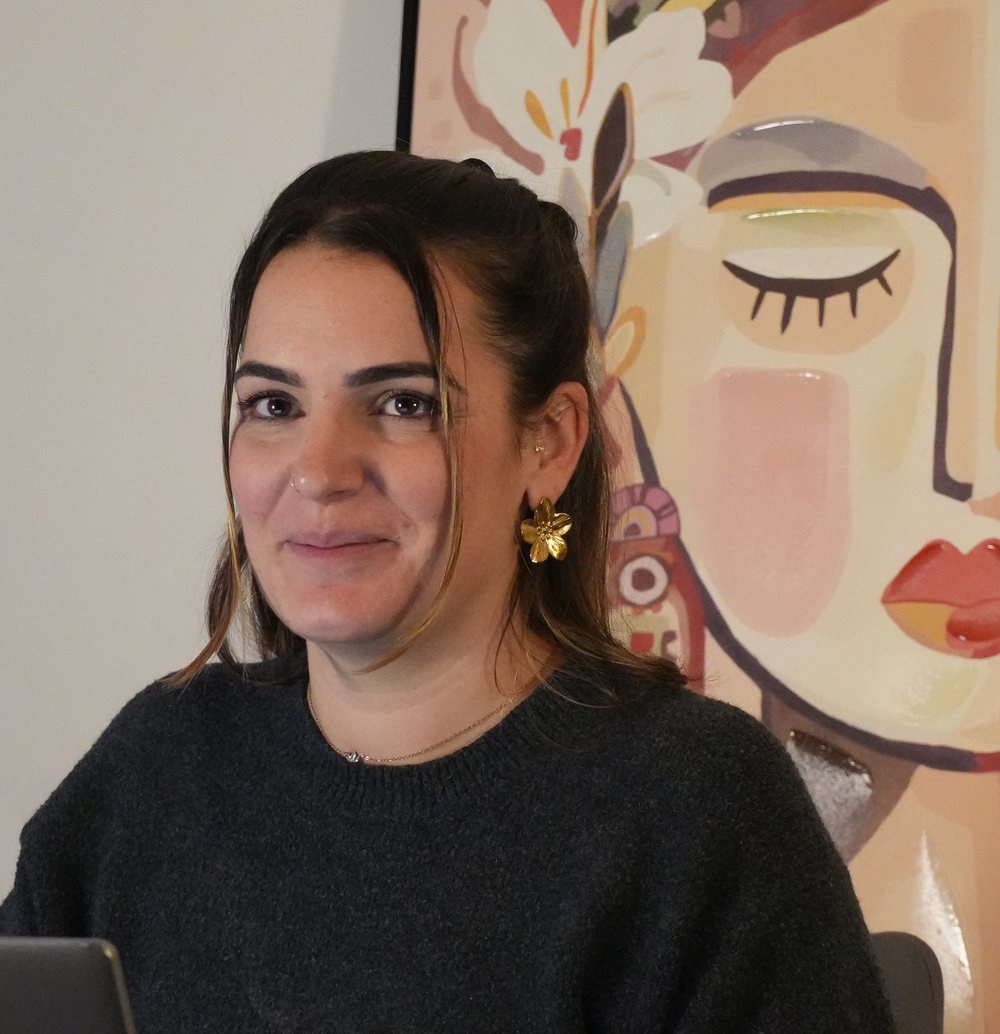 Émilie, fondatrice de Bienvenue Chez Nous, souriante devant un tableau aux tons poudrés